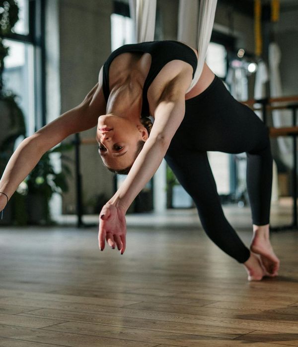Woman practicing graceful yoga flow in a dark studio with cyan lights
